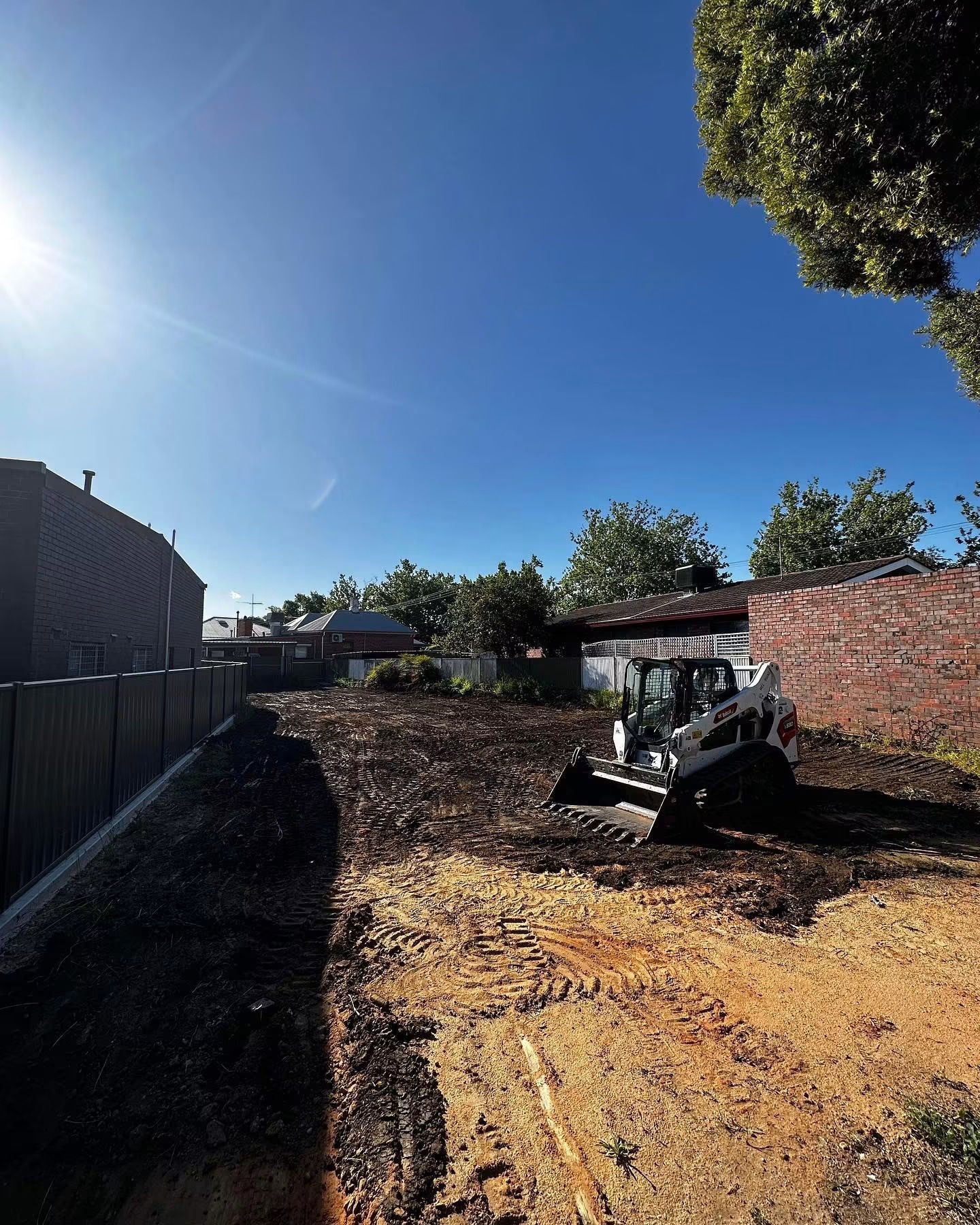 Skid-steer clearing and levelling a rural site